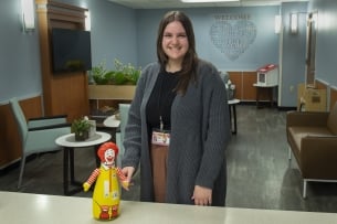 A student stands in a medical clinic next to a small Ronald McDonald toy.